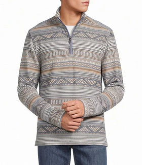 A man wearing a quarter-zip long-sleeve pullover sweater with a gray, beige, and white geometric pattern, paired with blue jeans against a plain white background.