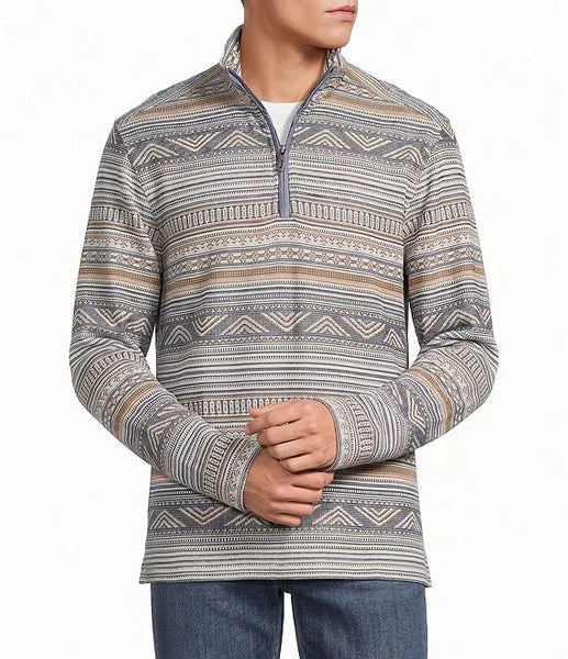 A man wearing a quarter-zip long-sleeve pullover sweater with a gray, beige, and white geometric pattern, paired with blue jeans against a plain white background.
