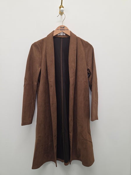 A brown suede-like open-front coat or robe hanging on a wooden hanger against a plain light gray wall.