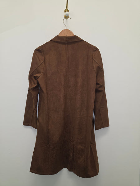 A brown suede long-sleeve coat hanging on a wooden hanger against a plain off-white wall.