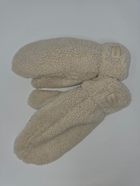 A pair of cream-colored, plush fleece mittens with small tan brand tags on the wrist area, laid flat on a light gray background.