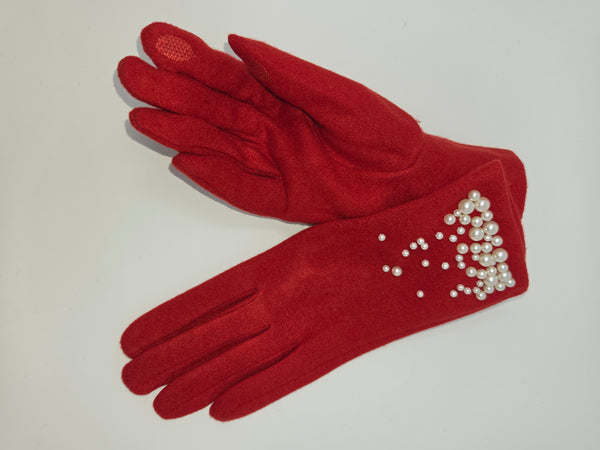 A pair of red suede-like gloves with white faux-pearl embellishments on the cuffs, one glove showing a textured dot-pad on the back of the hand, laid flat on a light gray background.