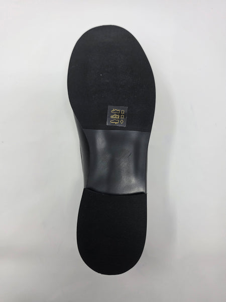 The black rubber outsole of a shoe, showing a small gold-colored size sticker with '9.5' on the heel area, photographed against a plain white background.