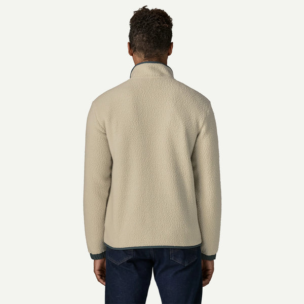 A man viewed from the back wearing a light beige sherpa fleece quarter-zip pullover with dark green ribbed trim on the collar, cuffs, and hem, paired with dark blue jeans, against a plain off-white background.