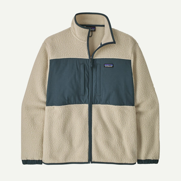 A Patagonia fleece jacket in a colorblock design with a beige sherpa body, a dark slate blue-gray horizontal chest panel, and dark navy trim on the collar, zipper, and cuffs. The Patagonia logo is visible on the chest.