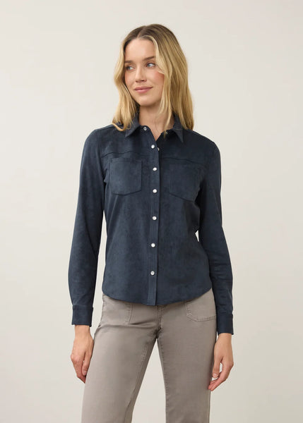 A woman modeling a dark navy blue long-sleeve button-up shirt with a western-style collar and chest pockets, paired with gray pants, against a plain light gray studio background.