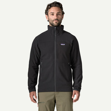 A man wearing a black Patagonia full-zip fleece jacket with a stand-up collar and zippered hand pockets, paired with khaki pants, against a plain white background.