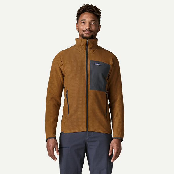 A man wearing a brown textured zip-up fleece jacket with a dark gray chest pocket and Patagonia logo, paired with dark gray pants, against a light gray background.