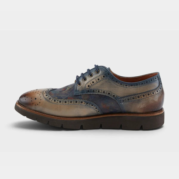 A single men's wingtip oxford shoe with a distressed leather finish, featuring a blue and brown colorway with a dark brown sole, shown in a side profile on a light gray background.