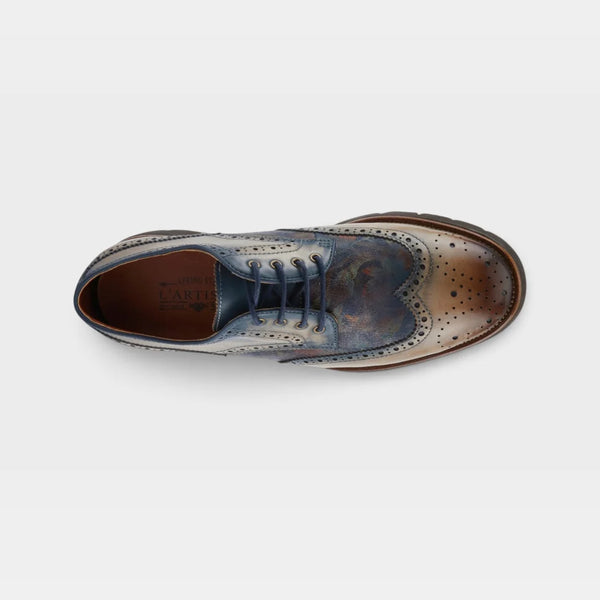 A single men's wingtip oxford shoe shown from a top-down view on a light gray background. The shoe features a distressed leather upper with a color-shifting finish that transitions from blue and brown to bronze/copper, with dark brown laces and a dark brown sole.