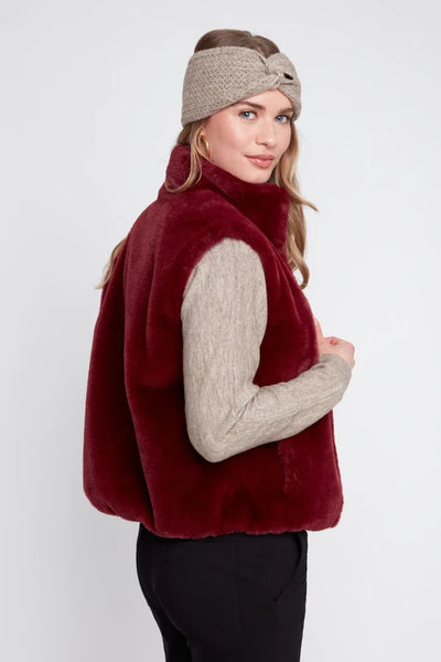 Woman wearing a red fur vest and beige headband on a white background