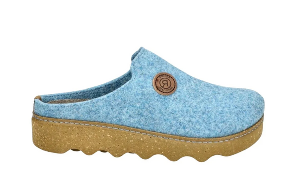 A light blue felt clog shoe with a natural brown cork platform sole and a circular brown brand patch on the side, shown against a plain white background.