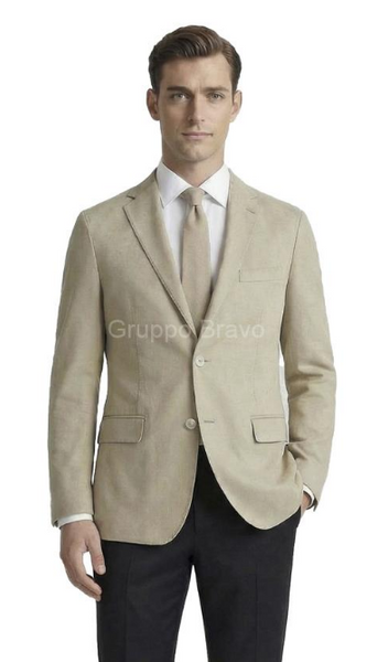 A man wearing a light beige textured blazer over a white dress shirt and beige tie, paired with dark trousers, against a plain white background.