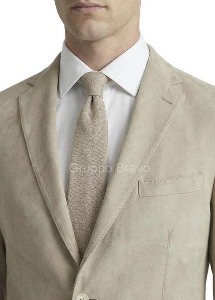 A close-up of a man wearing a light beige textured suit jacket, a matching beige tie, and a white dress shirt. A semi-transparent 'Gruppo Bravo' watermark is visible across the center.