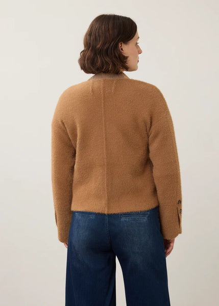 A woman shown from the back wearing a camel brown fuzzy cropped cardigan and dark blue jeans, photographed against a plain light background.