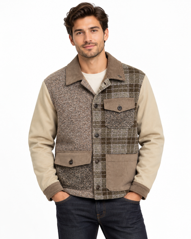 A man wearing a brown and beige plaid button-up jacket with solid beige sleeves, paired with a white t-shirt and dark blue jeans, against a plain white background.